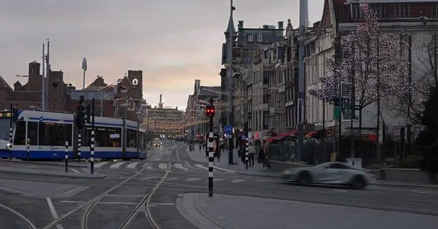 A photo of an Amsterdam street with a tram and canal houses