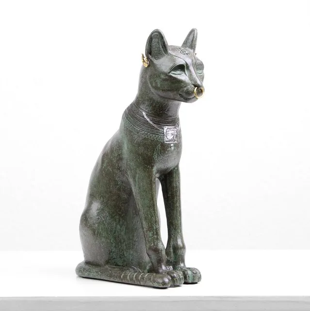 Studio photo of a green-patinated Gayer-Anderson cat replica statue with gold nose ring, on a white sweep